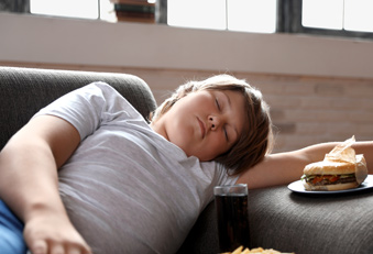 Junge mit Fastfood auf dem Sofa