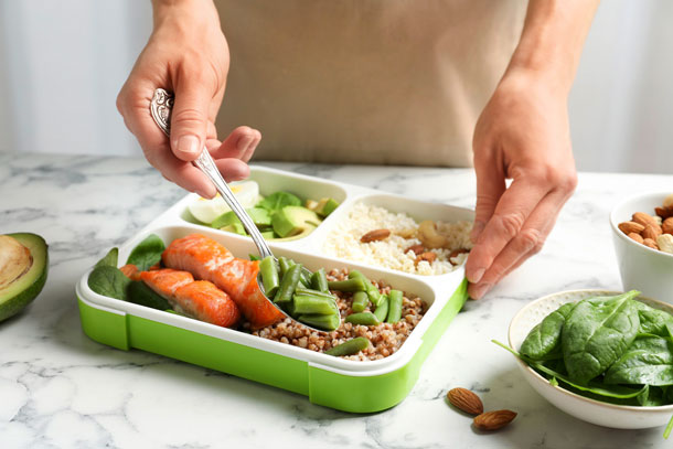 Gesundes Essen von daheim zur Arbeit mitnehmen. (Foto: 123RF, belchonok) Eine Frau bereites ihre Luchbox mit frischen und gesunden Zutaten vor.