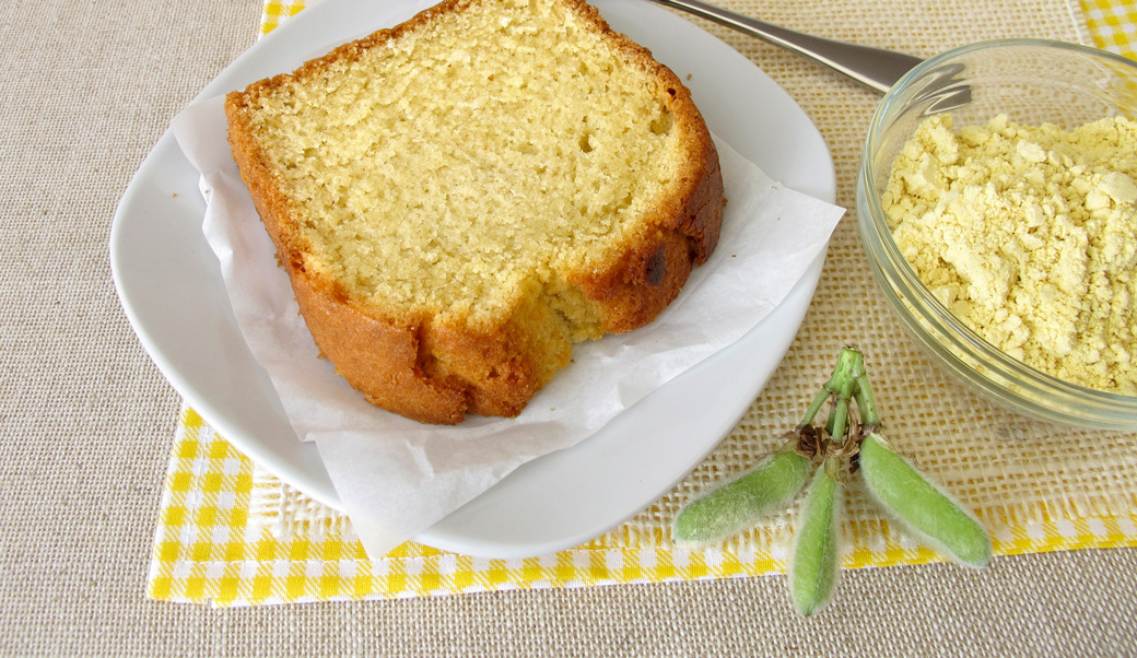 Un morceau de gâteau jaune se trouve sur une assiette. A côté se trouve un bol de farine de lupin jaune.