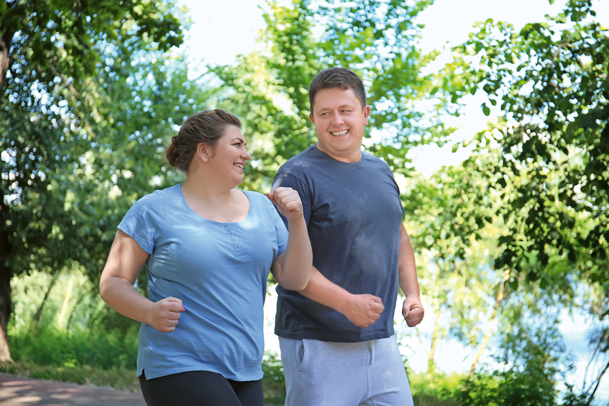 L'exercice fait partie d'un mode de vie sain. (Photo: 123RF, serezniy) Un couple motivé en surpoids fait du jogging dans un parc verdoyant.