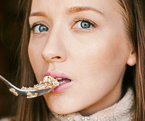 Ernährung und Psyche (Foto: 123RF) Eine Frau isst ein vollwertiges Müesli.